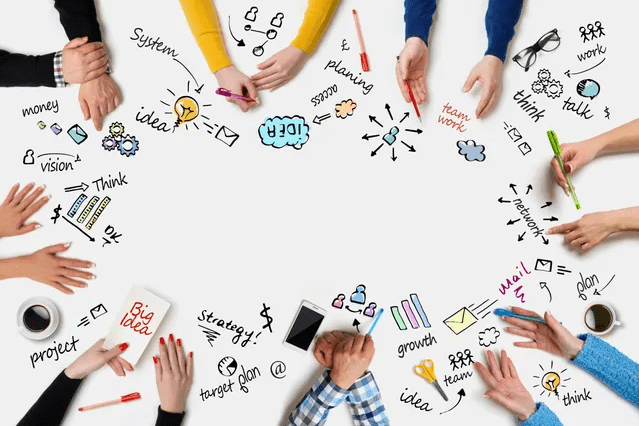 People collaborating around a table with brainstorming sketches and notes.